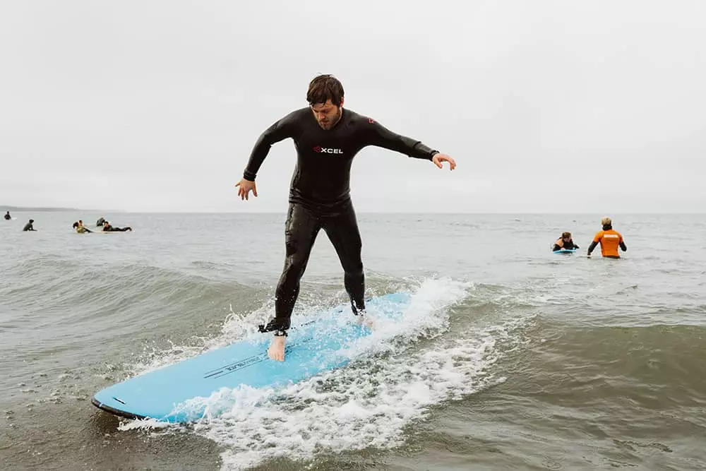 adult man learning to surf at group surf lesson