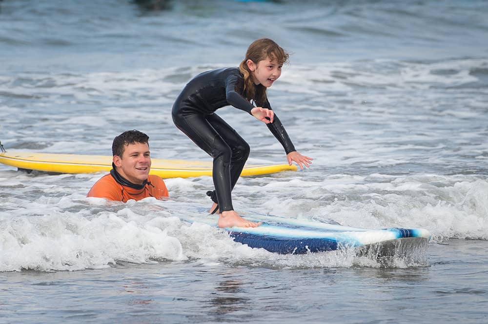 instructor teaching surfing to young girl