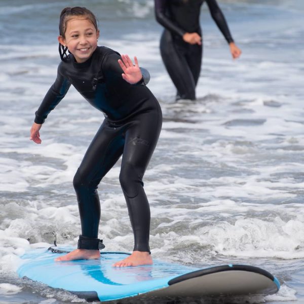 young girl learning to surf on small wave