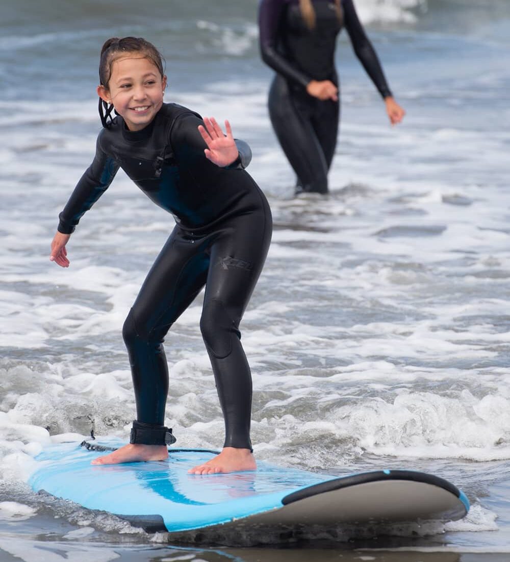 young girl learning to surf on small wave